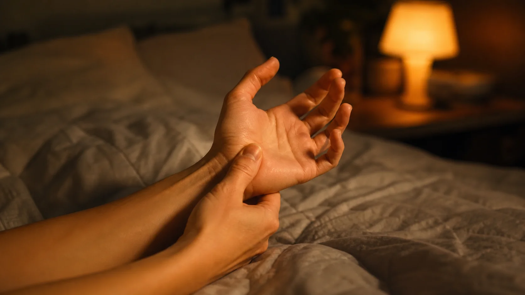 Hands being stretched in warm lamplight at night